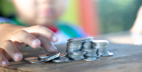 The boy hand holding money coin and stack with layered coin is much more. Business and Finance concept. Money saving concept.