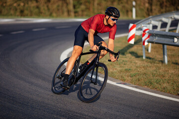 Male athlete in protective helmet biking on asphalt road