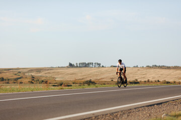 Active young man cycling on road during sunny day