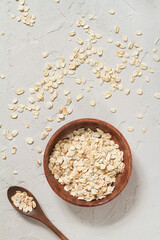 Whole oat flakes in wooden bowls on a light cement background, tinted