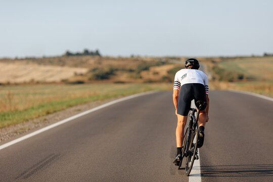Back view of athlete in helmet cycling outdoors