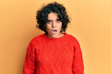 Hispanic woman with curly hair wearing casual winter sweater hugging oneself happy and positive from backwards. self love and self care
