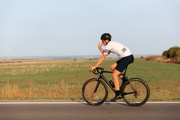 Sporty man with muscular body cycling on road