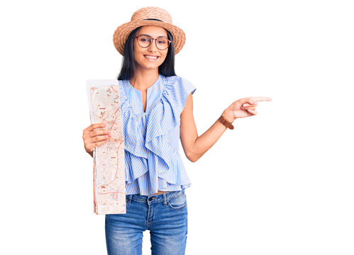 Young beautiful latin girl wearing summer hat holding map smiling happy pointing with hand and finger to the side