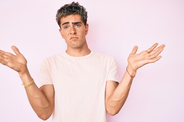 Young handsome man wearing casual clothes clueless and confused with open arms, no idea and doubtful face.