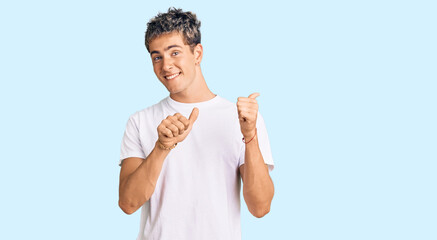 Young handsome man wearing casual white tshirt pointing to the back behind with hand and thumbs up, smiling confident