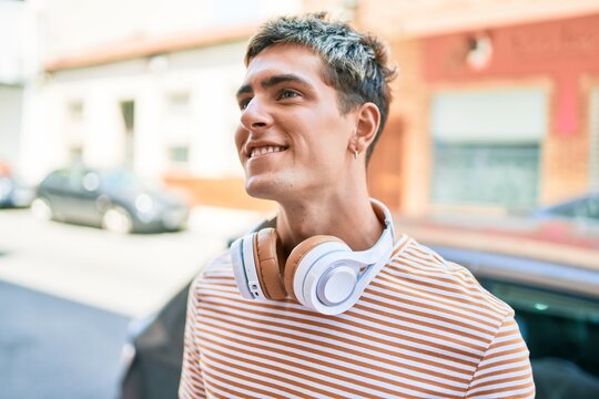 Young handsome caucasian man smiling happy wearing headphones walking at city.