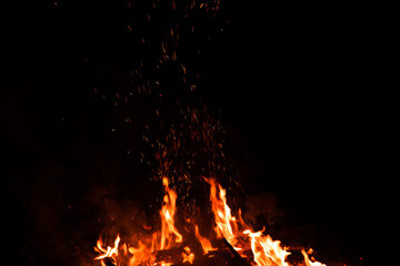 Fototapeta na wymiar Burning red hot sparks rise from large fire in the night. Fire flames sparks background. Abstract dark glitter fire particles lights.