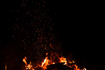 Burning red hot sparks rise from large fire in the night. Fire flames sparks background. Abstract...