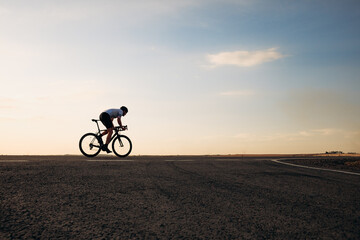Fototapeta na wymiar Handsome cyclist in sport clothing biking on road