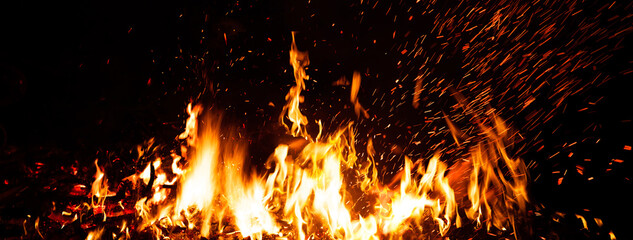 Fototapeta na wymiar Burning red hot sparks rise from large fire in the night. Fire flames sparks background. Abstract dark glitter fire particles lights.