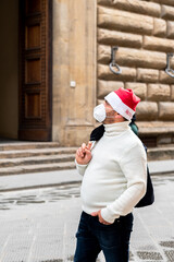 Fototapeta na wymiar Coronavirus and Christmas mood in Europe. man in protective medical mask and Santa hat in historic center of Florence Italy. Covid-19 quarantine in Europe Italy, France, Germany, Spain