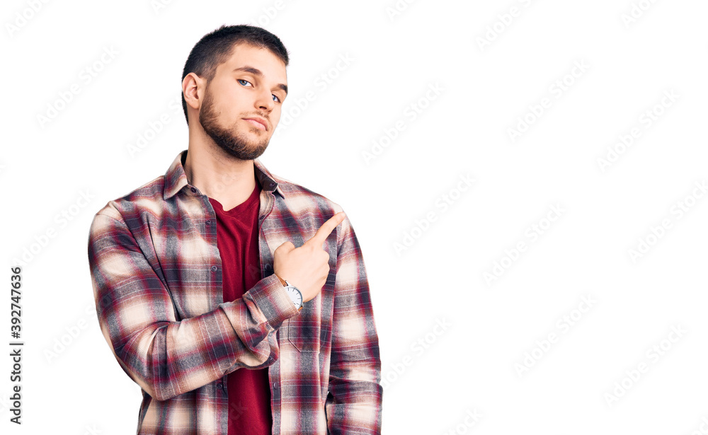 Wall mural young handsome man wearing casual shirt pointing with hand finger to the side showing advertisement,