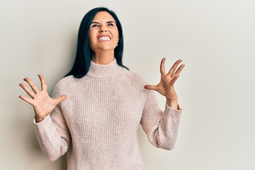 Young caucasian woman wearing casual winter sweater crazy and mad shouting and yelling with...