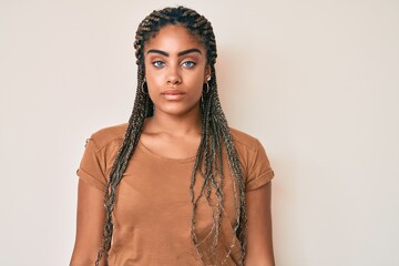 Young african american woman with braids wearing casual clothes with serious expression on face. simple and natural looking at the camera.