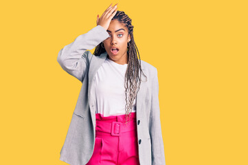 Young african american woman with braids wearing business clothes surprised with hand on head for...