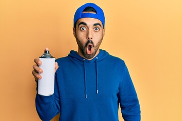 Young hispanic man with beard wearing sweatshirt holding graffiti spray smiling with an idea or question pointing finger with happy face, number one