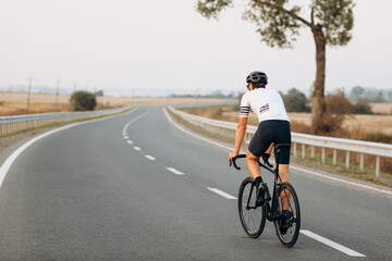 Back view of active man riding bike on fresh air