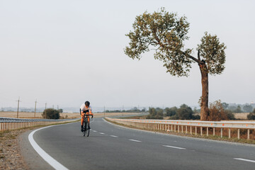 Obraz premium Muscular man riding bike with high speed on road