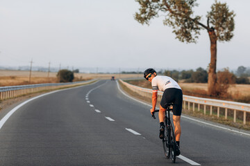 Young muscular guy in helmet riding bike on road