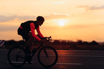 Male athlete in bright cycling clothing racing on road