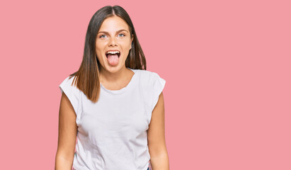 Fototapeta premium Young caucasian woman wearing casual white tshirt sticking tongue out happy with funny expression. emotion concept.