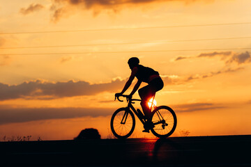 Fototapeta na wymiar Silhouette of active cyclist riding bike during sunset
