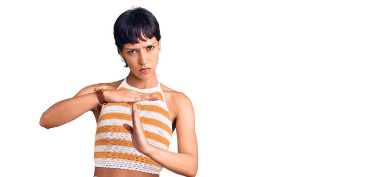 Young brunette woman with short hair wearing casual clothes doing time out gesture with hands, frustrated and serious face