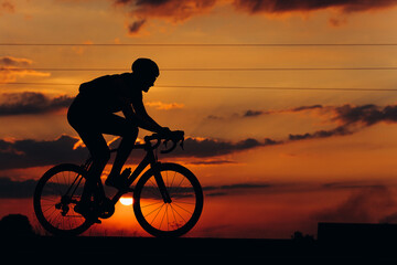 Obraz premium Athletic cyclist in silhouette racing on road