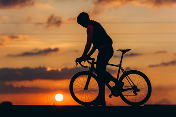 Obraz premium Athletic man in silhouette posing on camera with bike