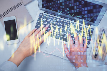 Double exposure of woman hands working on computer and forex graph hologram drawing. Top View....