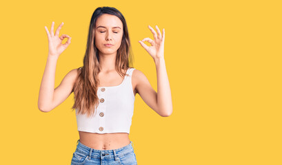 Young beautiful girl wearing casual sleeveless t shirt relax and smiling with eyes closed doing meditation gesture with fingers. yoga concept.