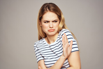 Fototapeta premium A woman with a displeased expression is gesturing with her hands T-shirt gray background