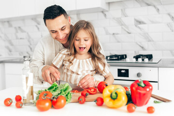Father's day. Dad and his child daughter are cooking and having fun together in the kitchen. Family holiday.