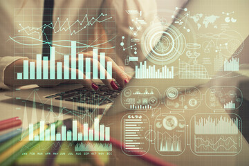 Double exposure of woman hands typing on computer and financial graph hologram drawing. Stock...