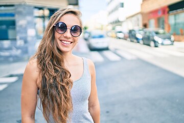 Young blonde woman smiling happy walking at street of city