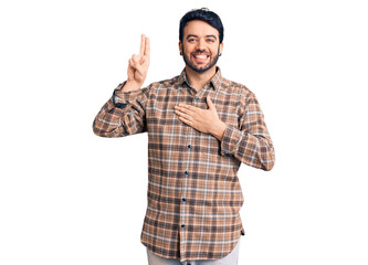Naklejka premium Young hispanic man wearing casual clothes smiling swearing with hand on chest and fingers up, making a loyalty promise oath