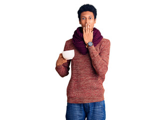 Young african american man wearing winter scarf and drinking a cup of hot coffee covering mouth...