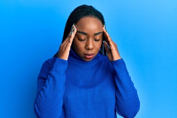 Young african american woman wearing casual winter sweater with hand on head for pain in head because stress. suffering migraine.