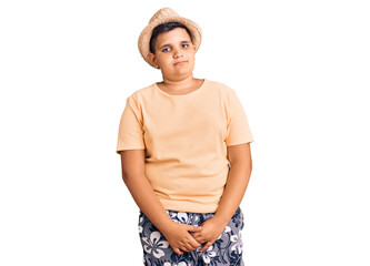 Little boy kid wearing summer hat and hawaiian swimsuit relaxed with serious expression on face. simple and natural looking at the camera.