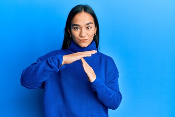 Young asian woman wearing casual winter sweater doing time out gesture with hands, frustrated and...