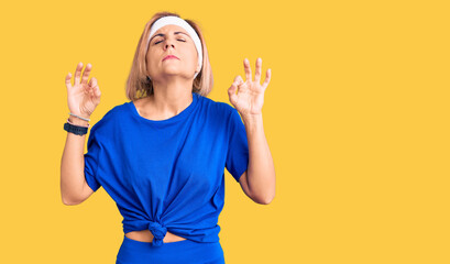 Young blonde woman wearing sportswear relax and smiling with eyes closed doing meditation gesture with fingers. yoga concept.