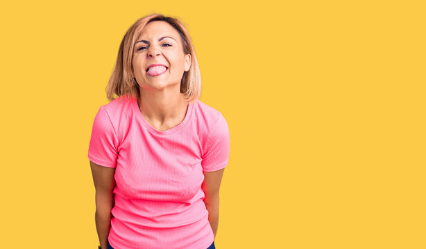 Young blonde woman wearing sportswear sticking tongue out happy with funny expression. emotion concept.
