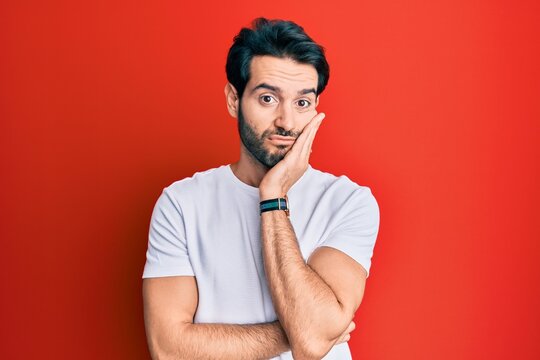 Young hispanic man wearing casual white tshirt thinking looking tired and bored with depression problems with crossed arms.