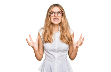 Beautiful young caucasian girl wearing casual clothes and glasses crazy and mad shouting and...