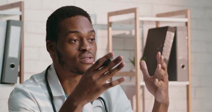 Professional medical consultation. African american doctor talking to patient at office, explaining treatment plan
