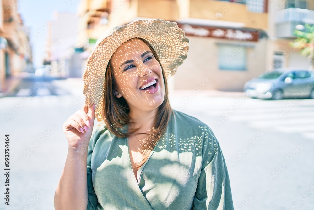 Wall mural Young hispanic woman on vacation smiling happy walking at street of city