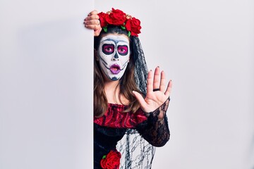 Young woman wearing day of the dead custome holding blank empty banner doing stop gesture with hands palms, angry and frustration expression