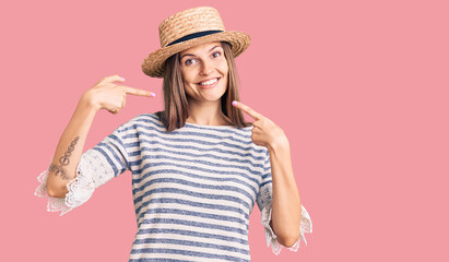 Beautiful caucasian woman wearing summer hat smiling cheerful showing and pointing with fingers teeth and mouth. dental health concept.