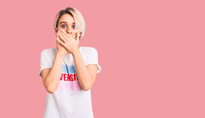 Young beautiful blonde woman wearing t shirt with diversity word message shocked covering mouth with hands for mistake. secret concept.